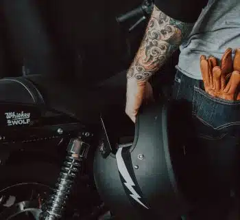 person in brown jacket and blue denim jeans riding on motorcycle
