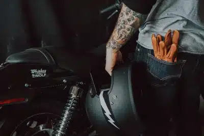 person in brown jacket and blue denim jeans riding on motorcycle