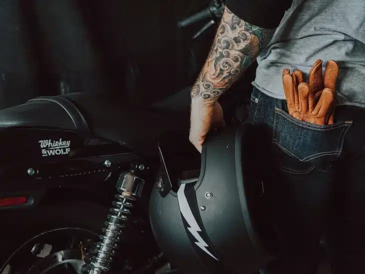 person in brown jacket and blue denim jeans riding on motorcycle