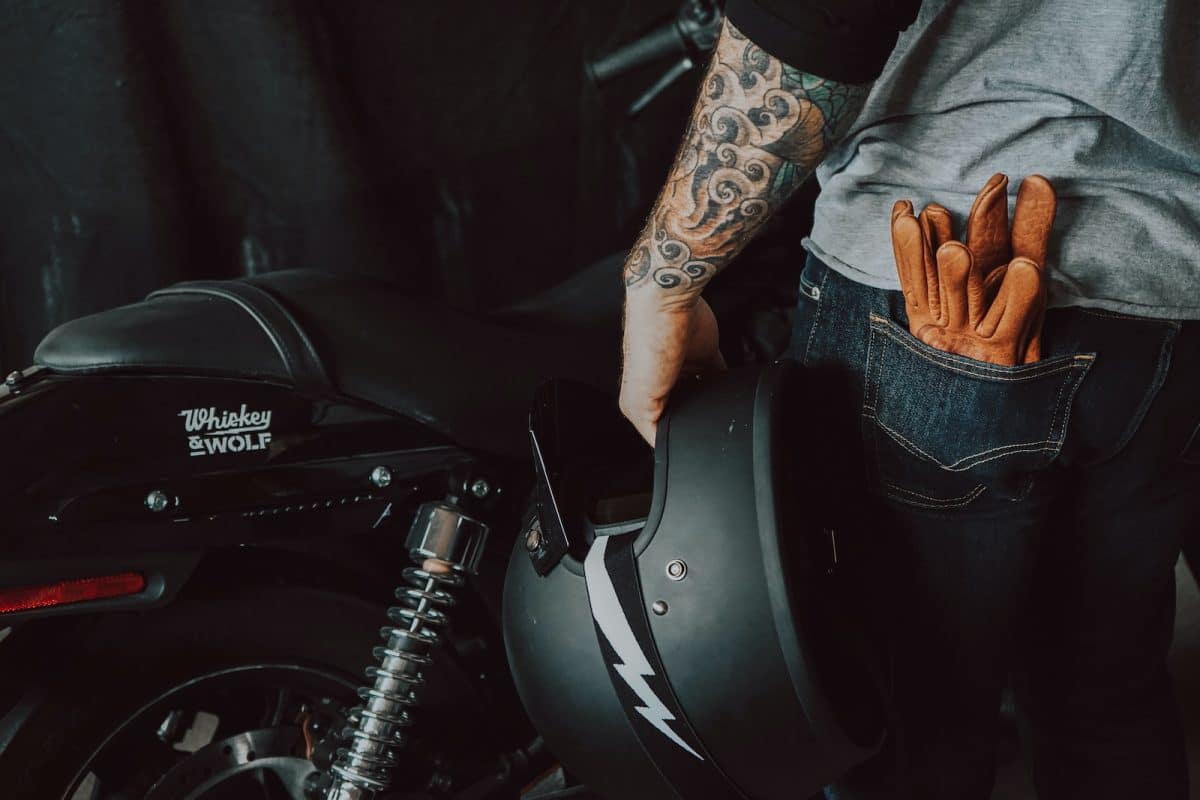 person in brown jacket and blue denim jeans riding on motorcycle