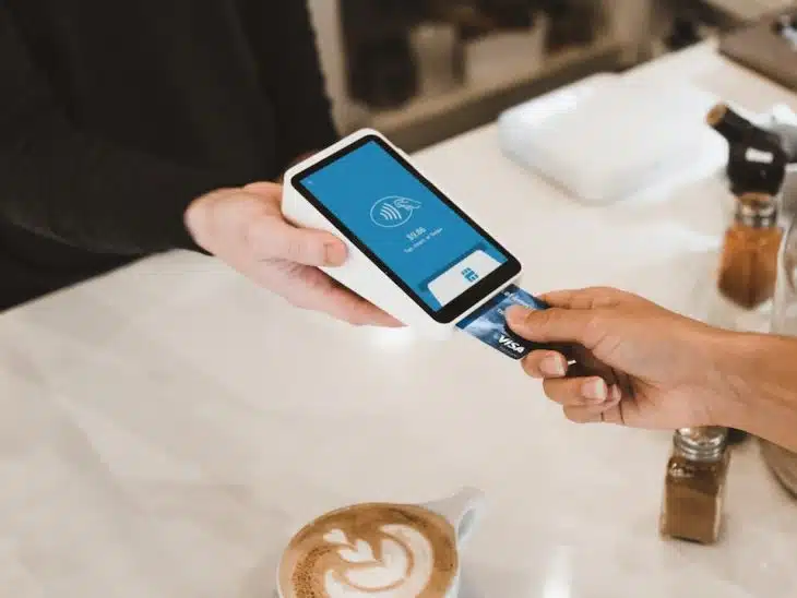 person putting magstripe card near black card terminal