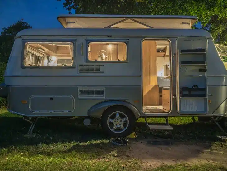 white and brown camper trailer beside tree